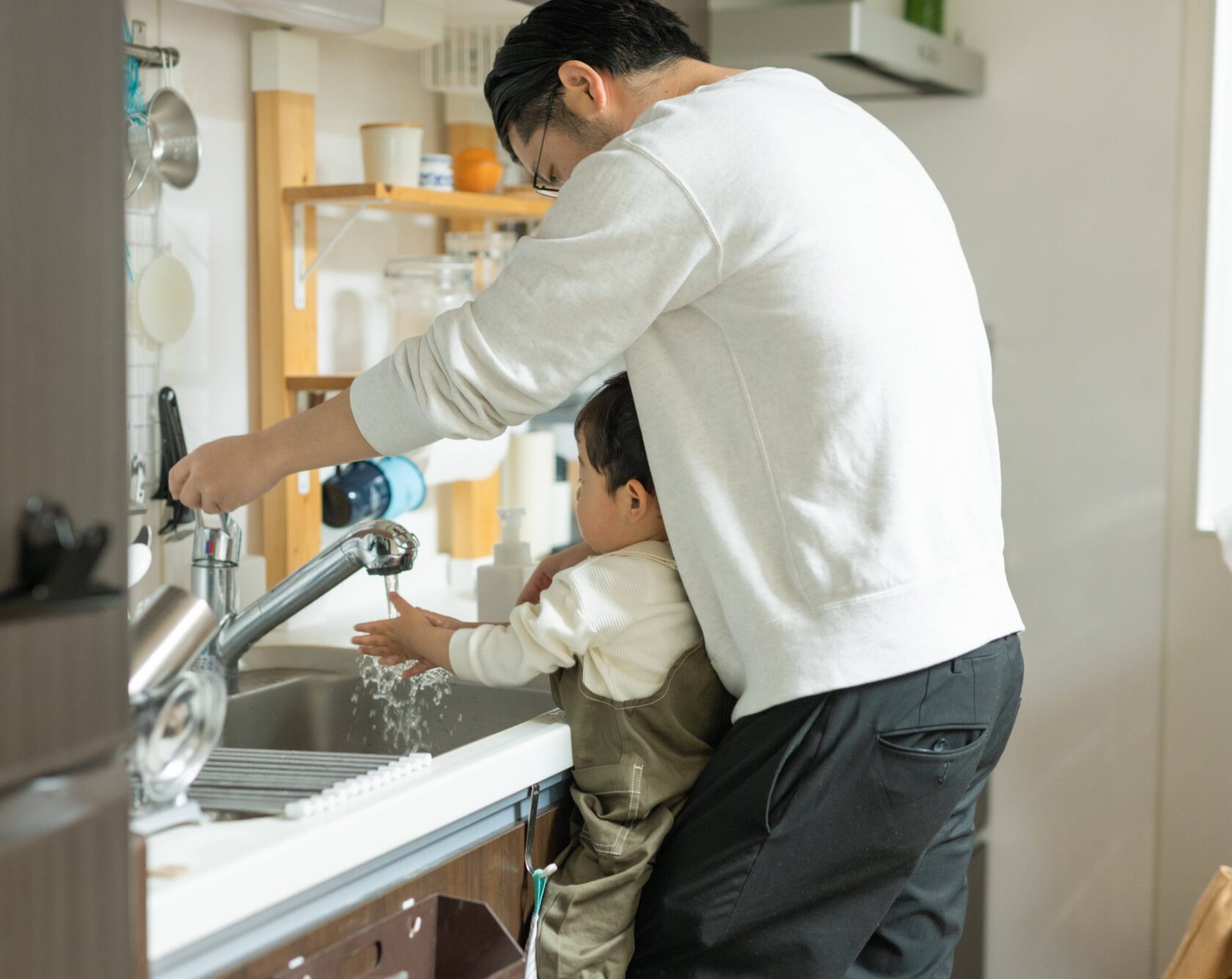 man and child washing hands under sink